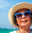 woman enjoys fun, visiting the sea, wearing a hat and wearing blue sunglasses