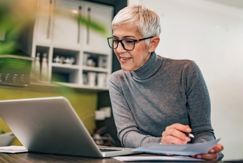 retired woman working at laptop on side hustle