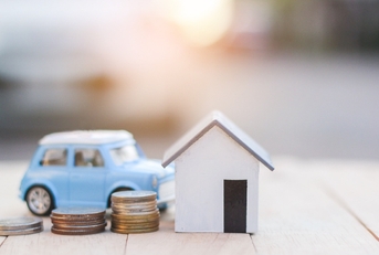 Coins next to a miniature house and car