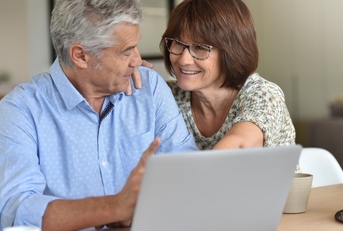 Senior couple talking and looking at computer