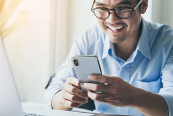 Smiling Asian man holding cellphone
