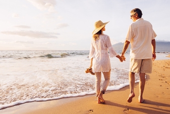 mature couple walking on the beach at sunset