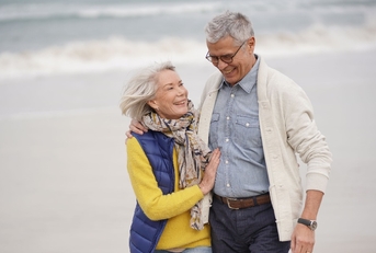 happy senior couple walking together on the beach