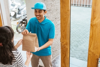 delivery man delivering food to a woman at home