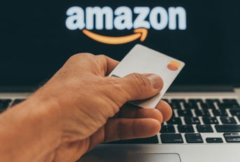 man holding a credit card in front of Amazon website