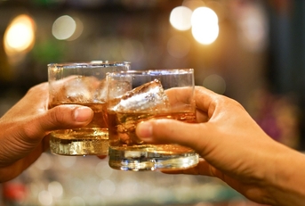 Two men clinking glasses of whiskey 