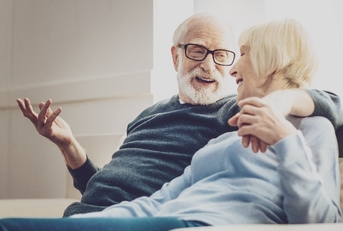 aged woman looking at her beloved man while listening to his jokes