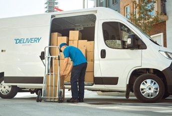 courier takes out cardboard box package from opened delivery van 