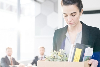 woman holding box of personal belongings leaving office