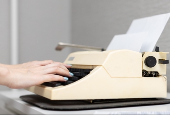 woman&#x27;s hand presses a finger on the buttons of an old typewriter