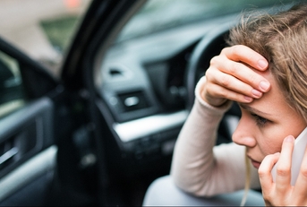 woman in the damaged car after a car accident making a phone call
