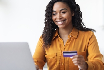 Woman looking at computer holding a credit card