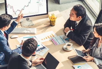 four people at a meeting studying charts