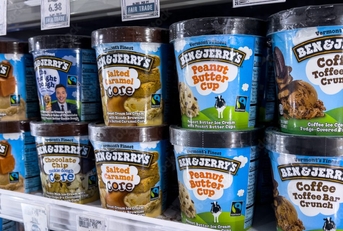 Pints of Ben &amp; Jerry&#x27;s ice cream stacked on a grocery store freezer shelf. 