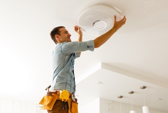 electrician is installing and connecting a lamp to a ceiling