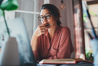 businesswoman thinking about something while sitting in front of laptop