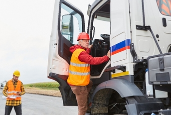 truck driver climbs into his truck with a delivery