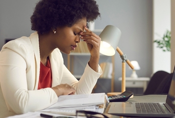  woman keeping eyes closed and massaging nose after working at laptop