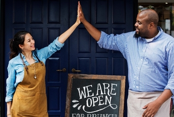 cheerful business owners standing with open blackboard