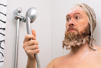 bearded man with soapy head standing in the bathroom