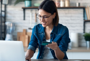 Woman holding credit card working on laptop