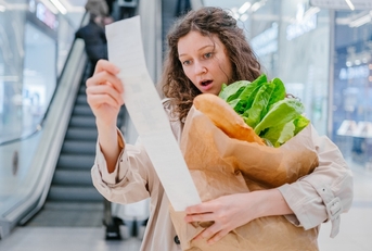 woman in shock looks into a paper check from a supermarket