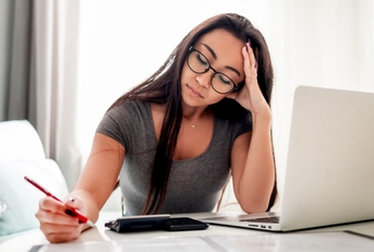 worried woman doing calculation in front of a laptop