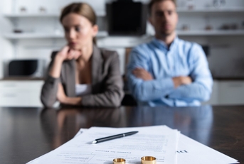 young depressed couple with divorce papers on table