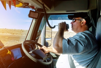 driver driving a truck white talking on radio