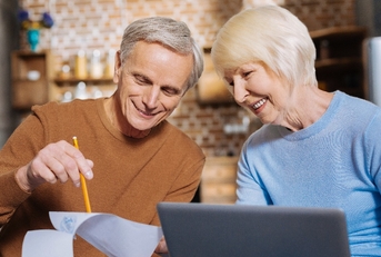elderly man holding his notes while showing them to a pleasant aged woman