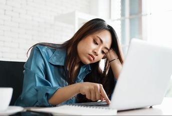 bored young asian woman typing laptop in office