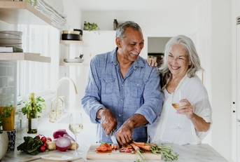 happy senior couple chopping vegetables in kitchen