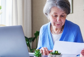 senior lady reading document and working on laptop