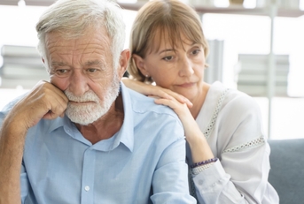senior couple sitting on couch having each other back