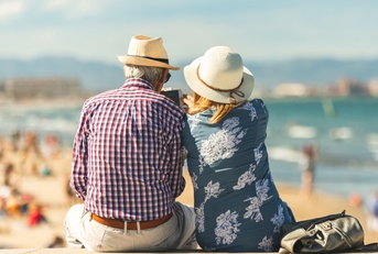 elderly couple sitting on the wall facing the beach