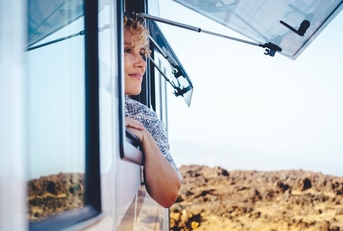 Woman smiling with head and arm over open RV window