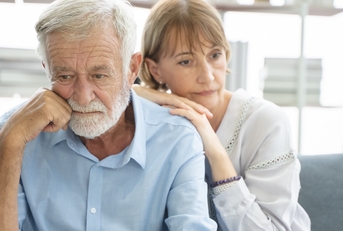 senior couple thinking while sitting on couch