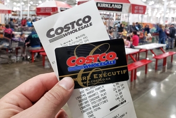 hand holding costco receipt with executive membership card at costco store