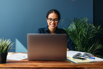 smiling entrepreneur sitting at home working on laptop