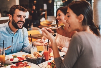 group of happy friends eating food at a restaurant