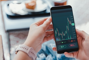 business woman sitting on couch checking stock graphs on smartphone