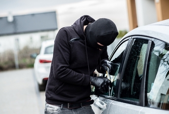 car thief trying to break into a car with a screwdriver