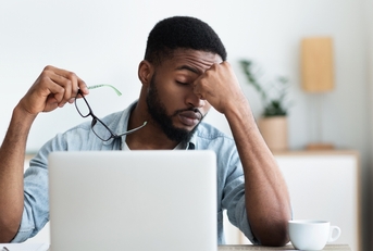 male employee having headache after working on laptop