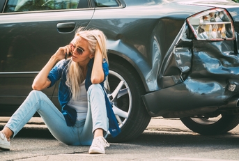 woman sits on the road near the broken car