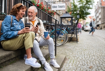 happy senior couple tourists sitting on stairs