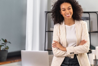 office worker stands with crossed arms near a desk
