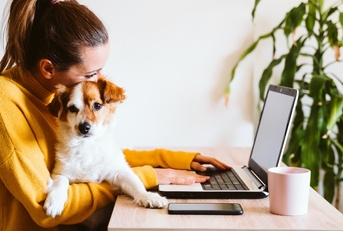Woman holding dog while she&#x27;s using a laptop