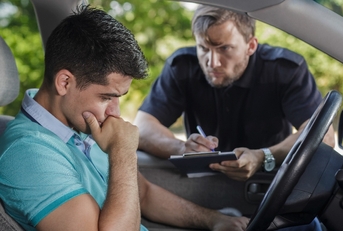 man sitting in car stressing as the police interviews him and write something on the clipboard