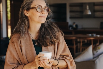 thoughtful senior woman holding a tea cup at home