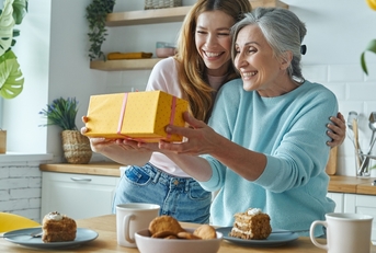 surprised senior mother receiving a gift box from her daughter